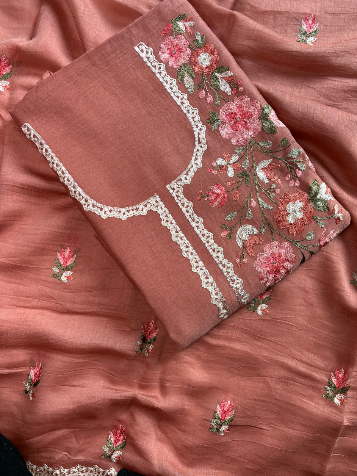 Detail of pink, ivory and green floral thread work on blush peach mul cotton