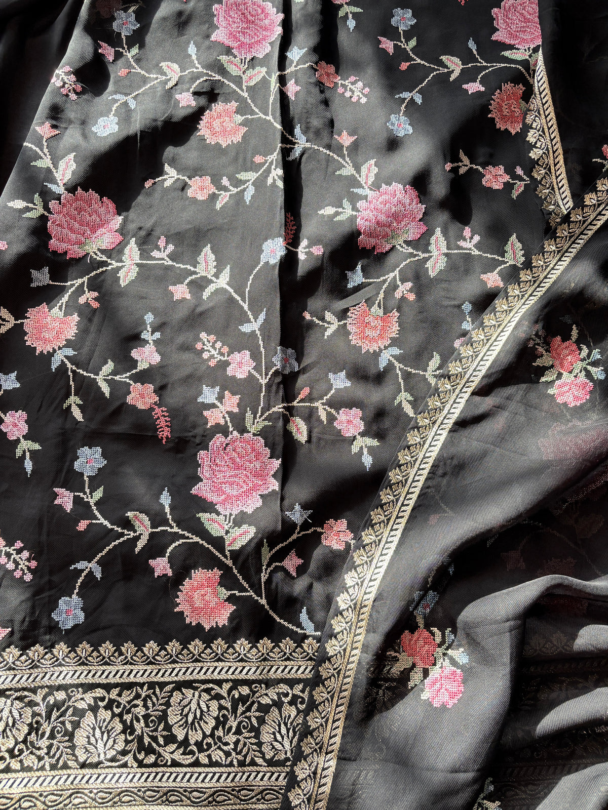 Black twill fabric with cross stitch florals and woven gold hem border